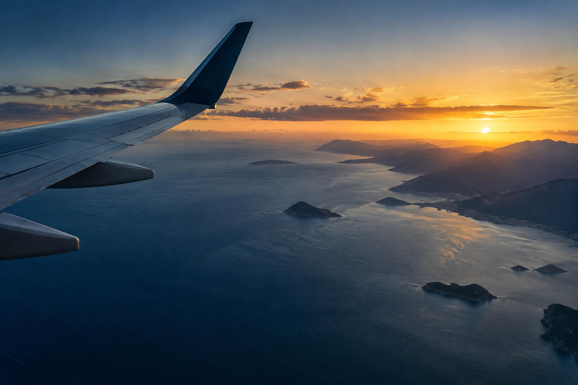Vista da asa de um avião sobre o litoral ao amanhecer